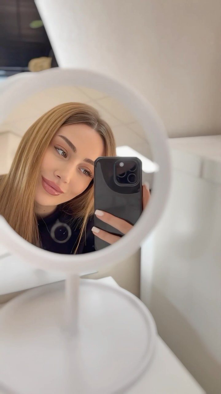 Ronde spiegel op een wit tafeltje in de salon